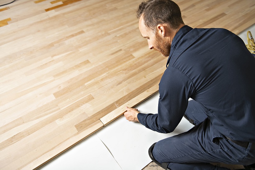 man installing wood floors in home