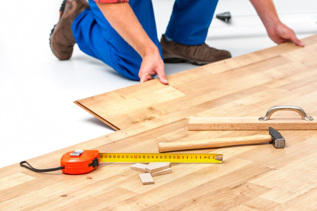 contractor with tools installing click-and-lock flooring