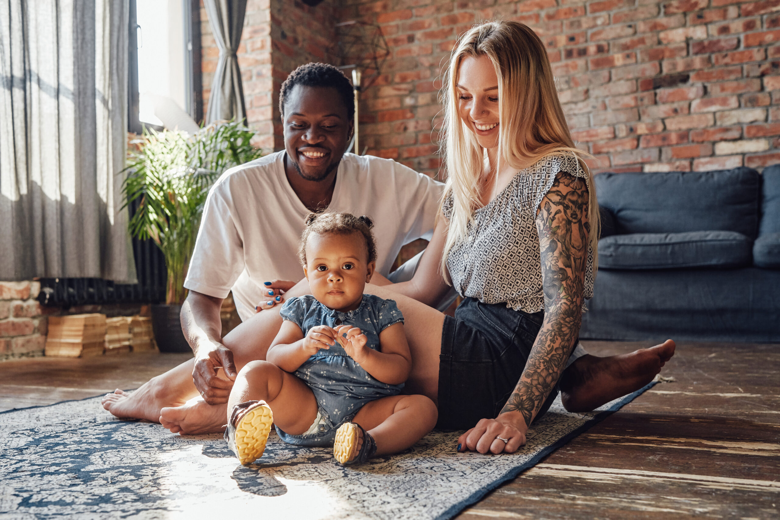 Shot of interracial family of two parents with their little daughter sitting on floor together.