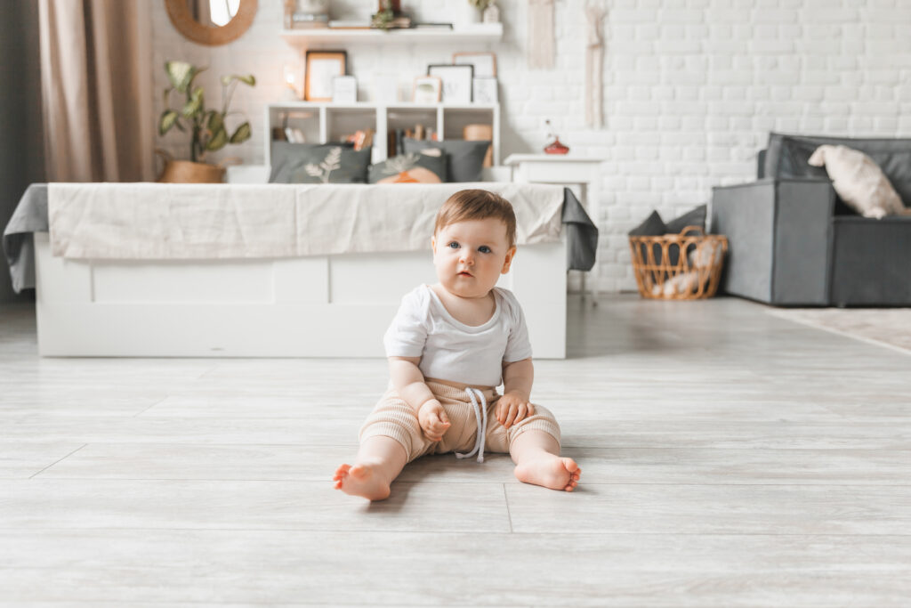 Portrait of a 7-9 month old baby in a home interior. A curious, smiling child explores the world around him. A cute baby is sitting on the floor.