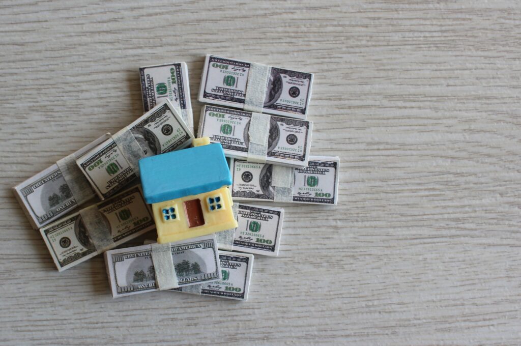 Property investment and house mortgage concept. Top view image of house on top of pile of money.