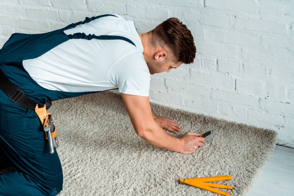 worker using cutter for carpet installation